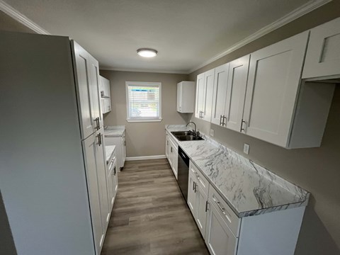 A kitchen with white cabinets and a marble countertop.