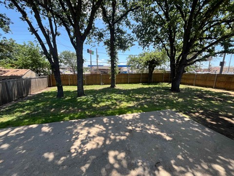 A backyard with a sand pit and trees.