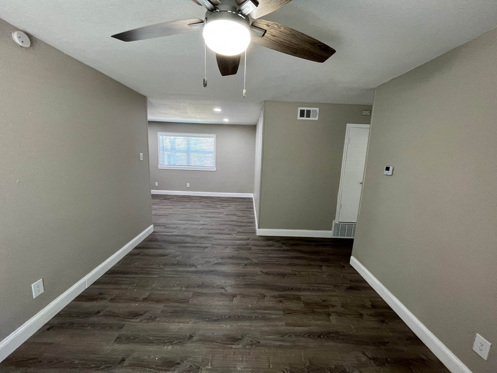 a empty living room with a ceiling fan and wood floors