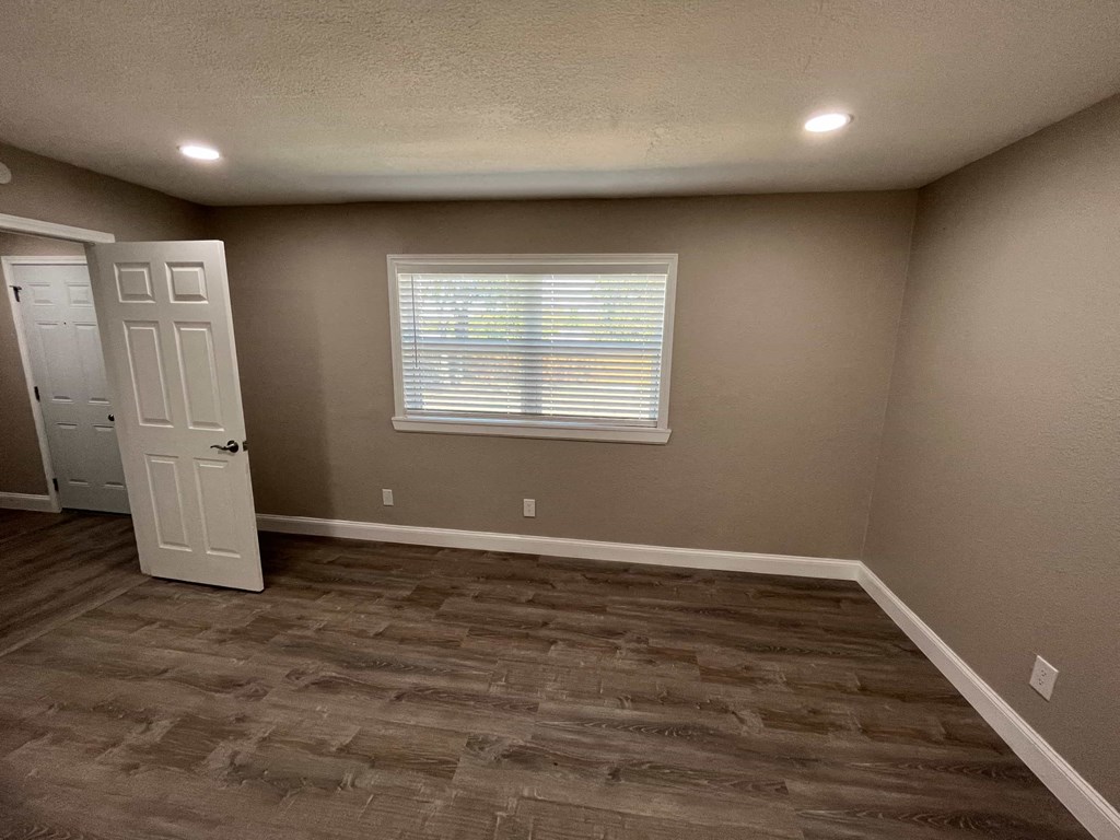 a empty room with wooden floors and a window and a door