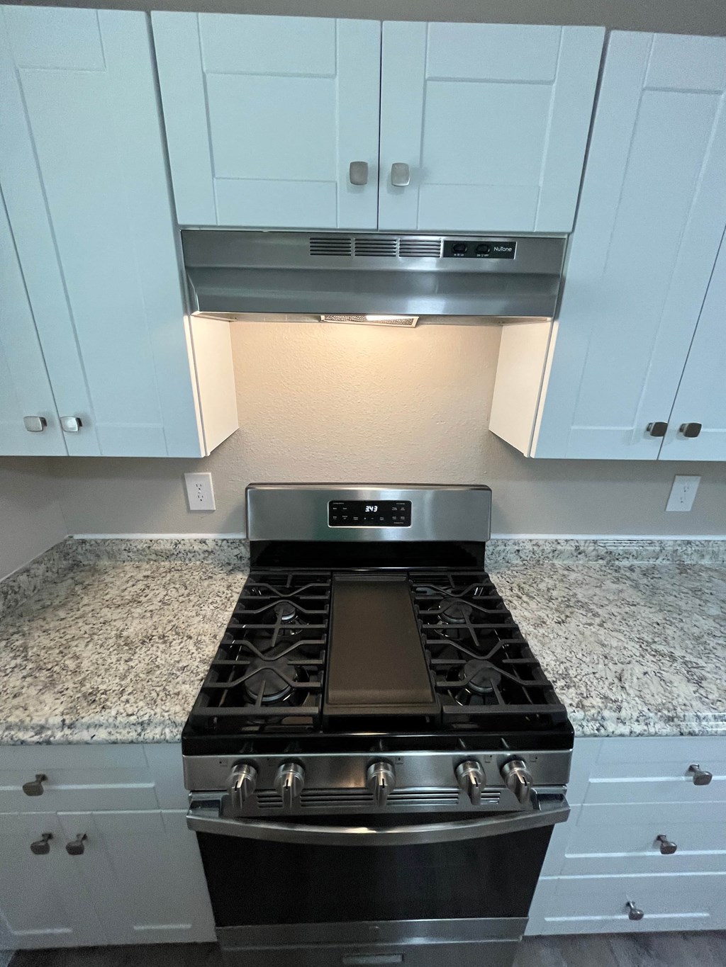 a kitchen with white cabinets and a stove and a microwave
