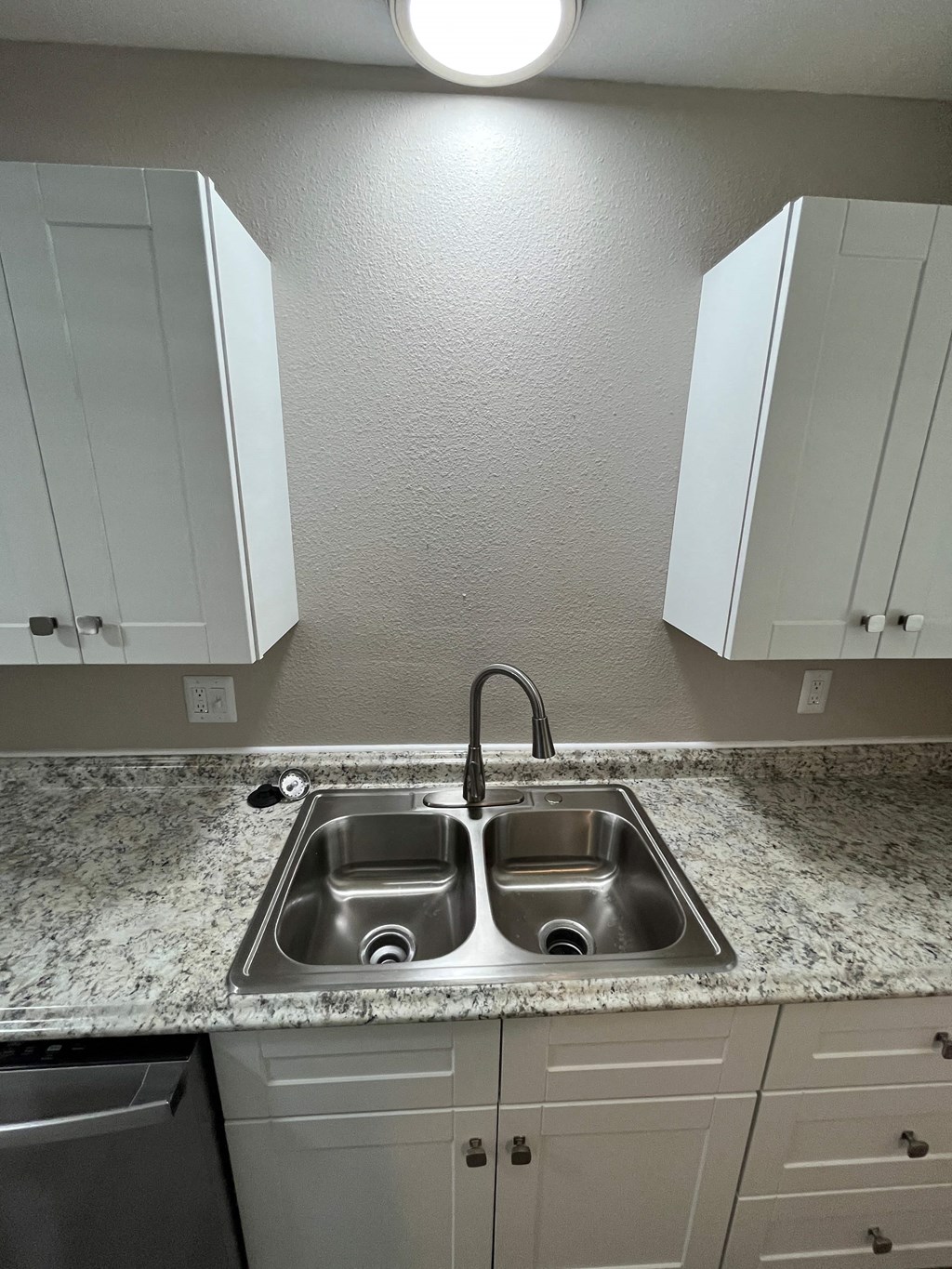 a kitchen with white cabinets and a stainless steel sink