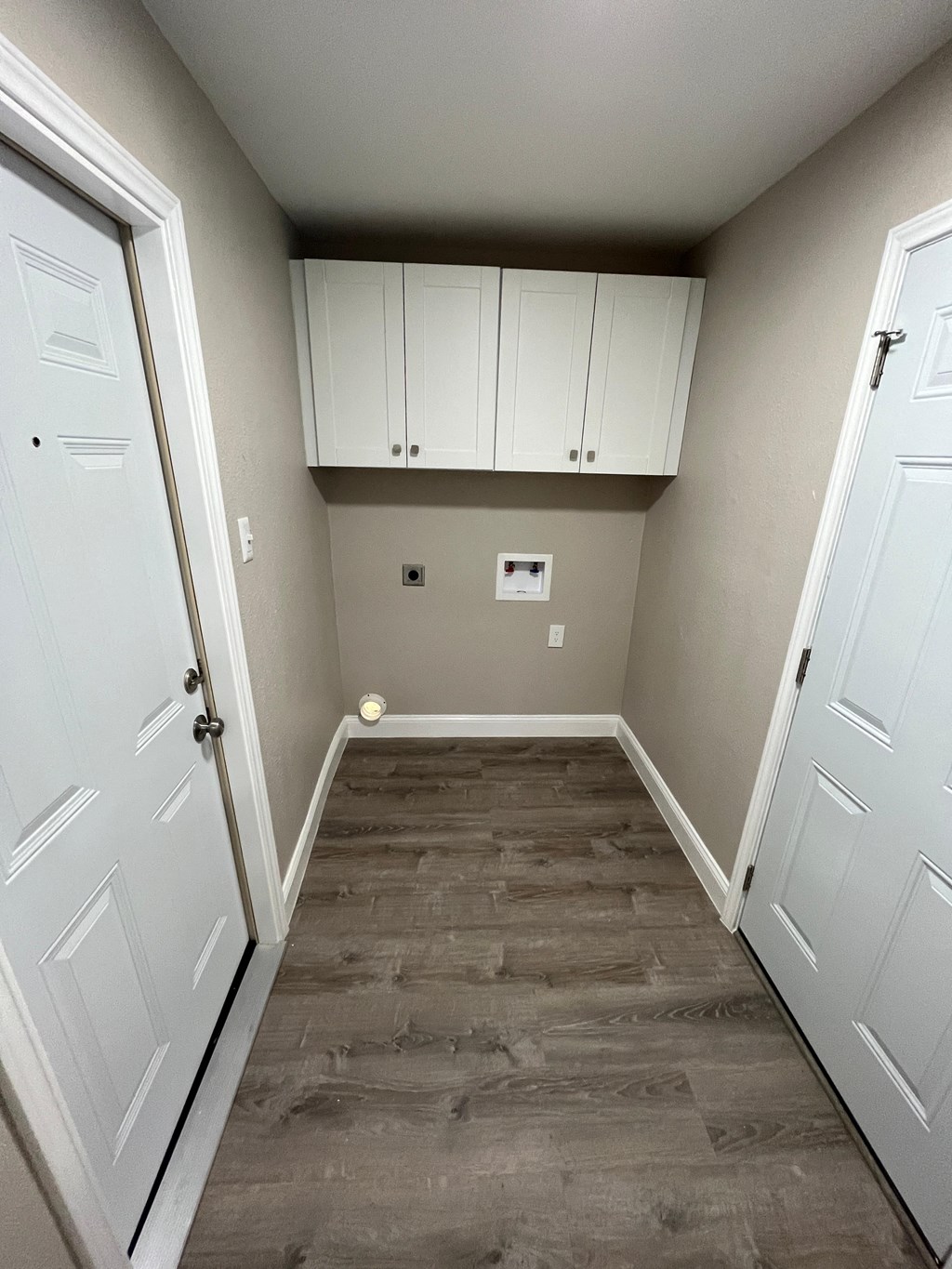 a empty room with a wood floor and white cabinets