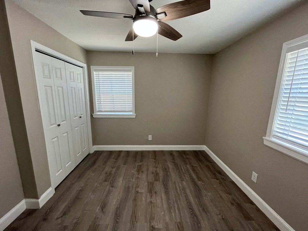 an empty bedroom with wooden floors and a ceiling fan