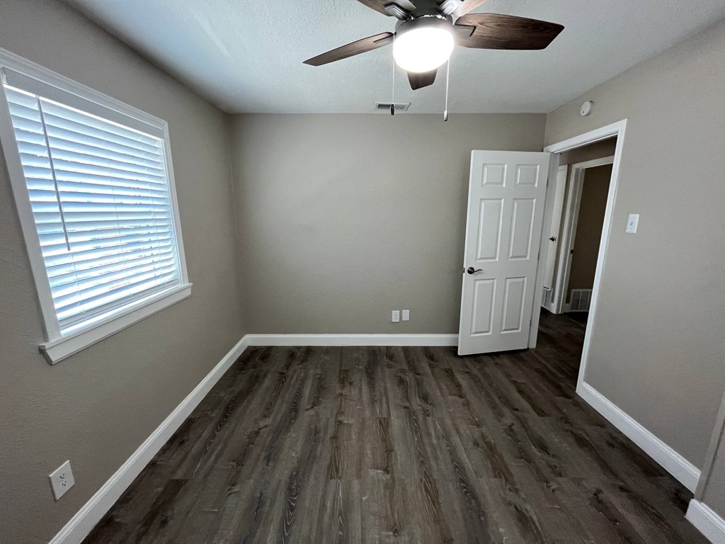 an empty living room with wooden floors and a ceiling fan