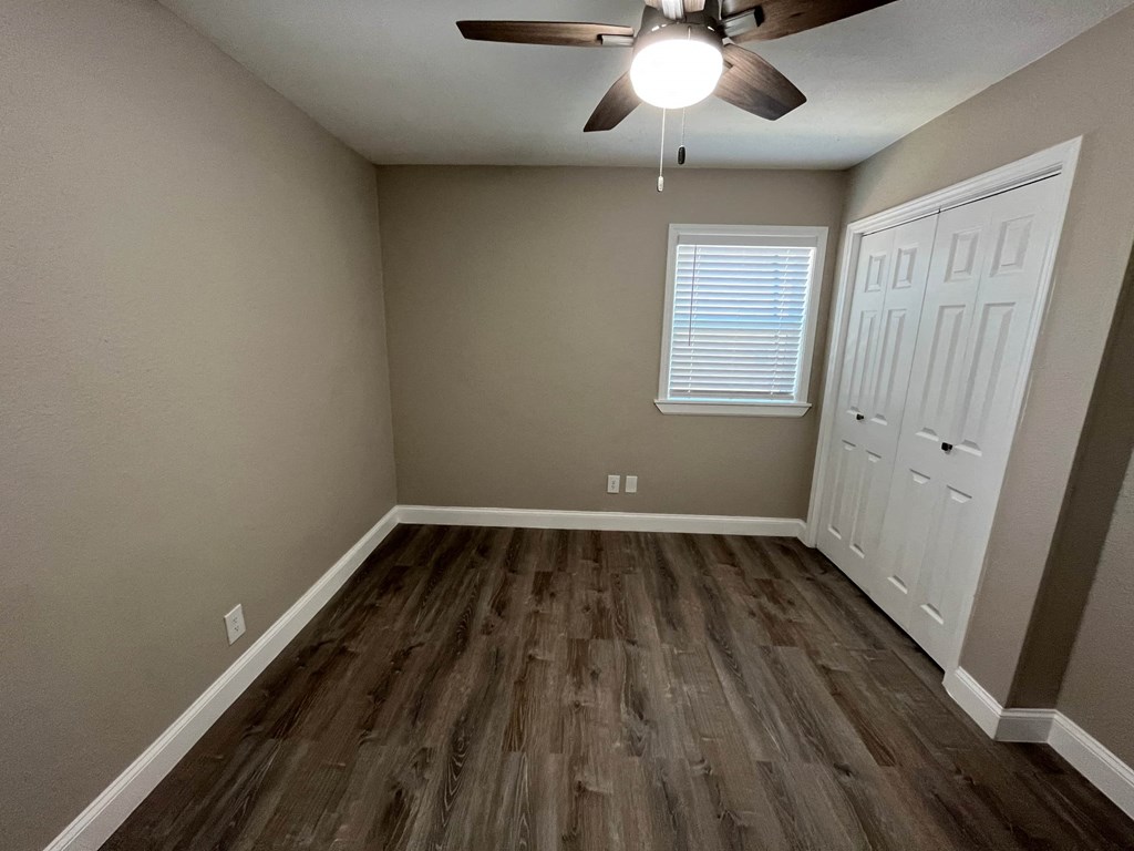 an empty room with wooden floors and a ceiling fan