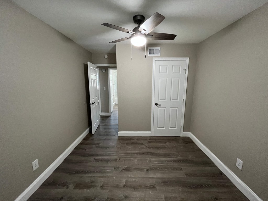 a room with a ceiling fan and a hallway with a door