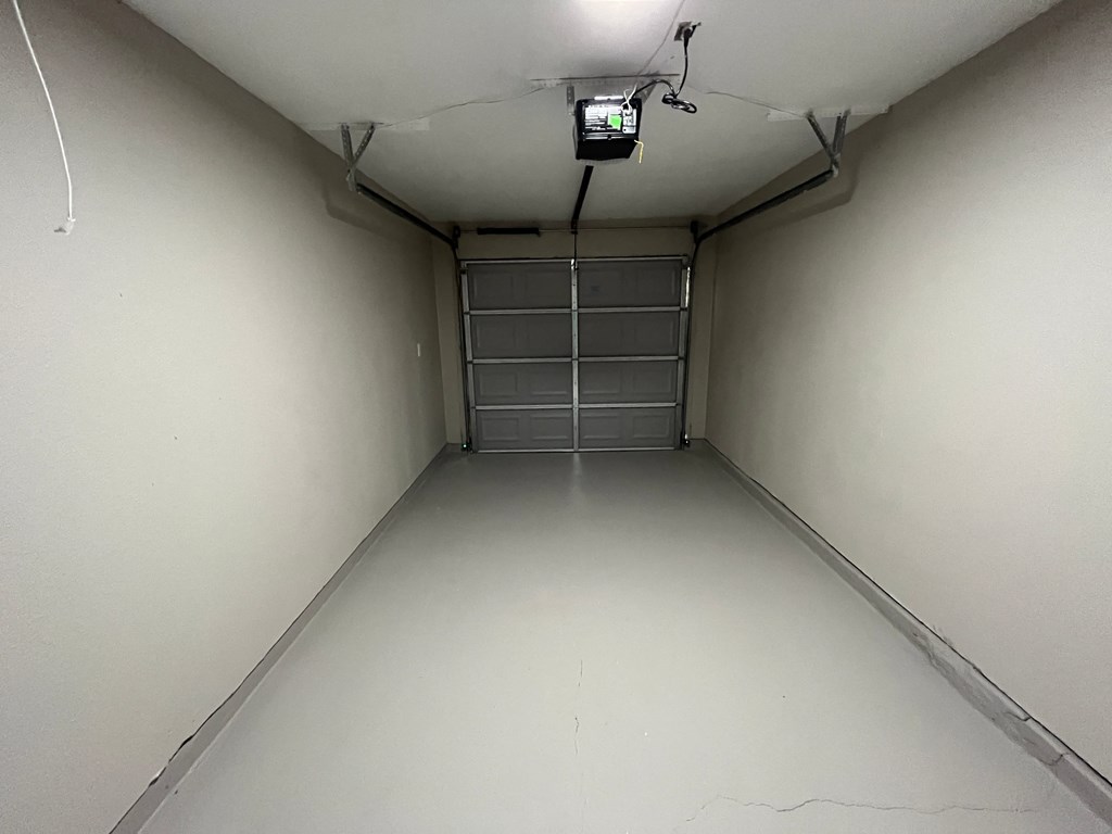 a long room with a white wall and a garage door