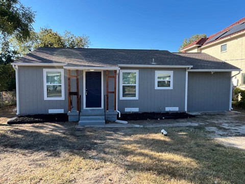 A grey house with a black door and windows.