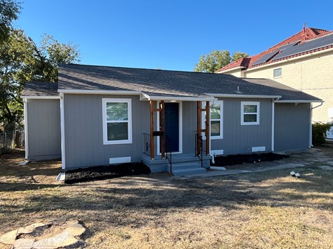 A grey house with a blue door and windows.