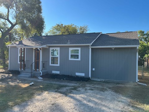 A house with a grey siding and a brown roof.
