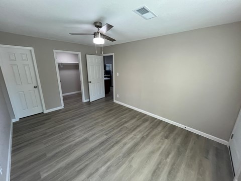 A room with a ceiling fan and light fixture, and a wooden floor.