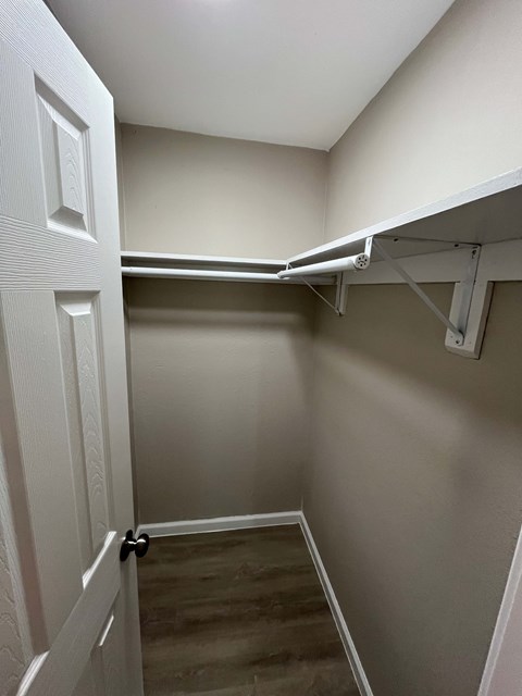 A white door is open to a hallway with a white shelf above.
