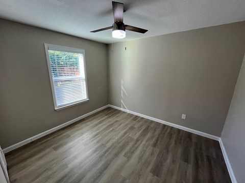 A room with a ceiling fan and a window with blinds.