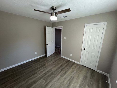 A room with a ceiling fan and two doors.