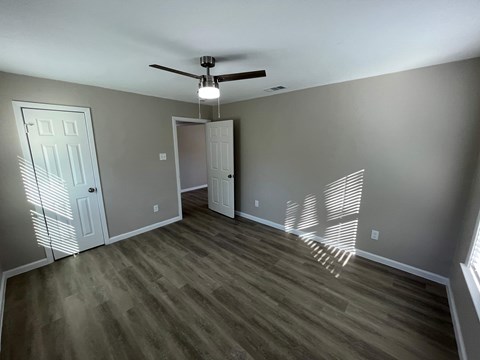 A room with a ceiling fan and two doors.