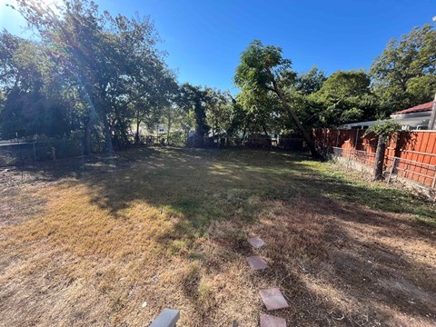 A backyard with a dirt path and a fence.