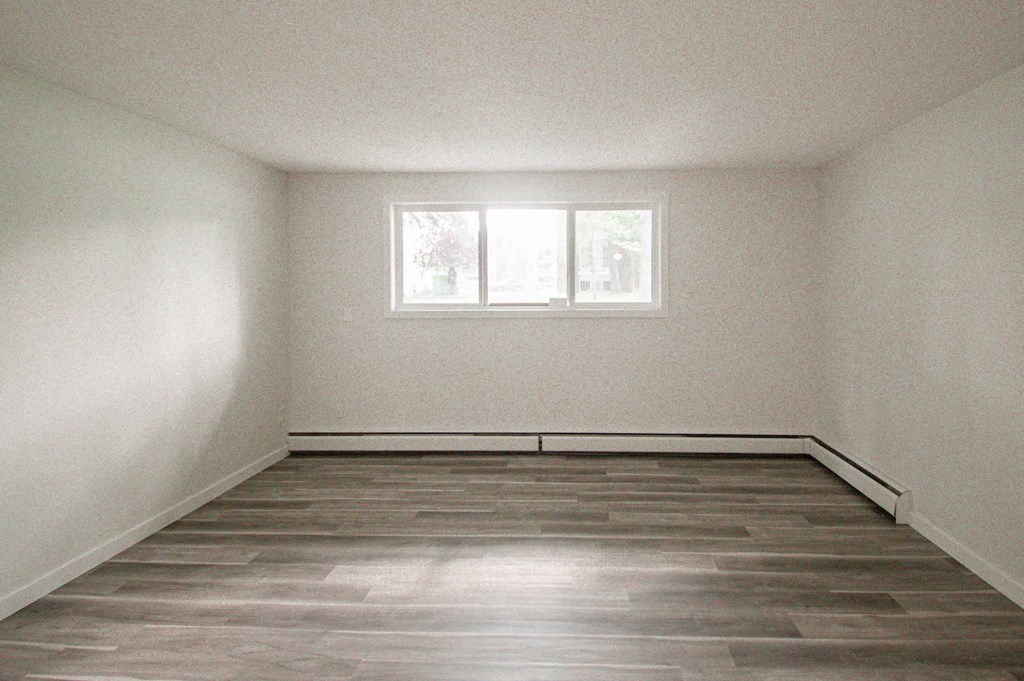 an empty room with a window and wooden floors