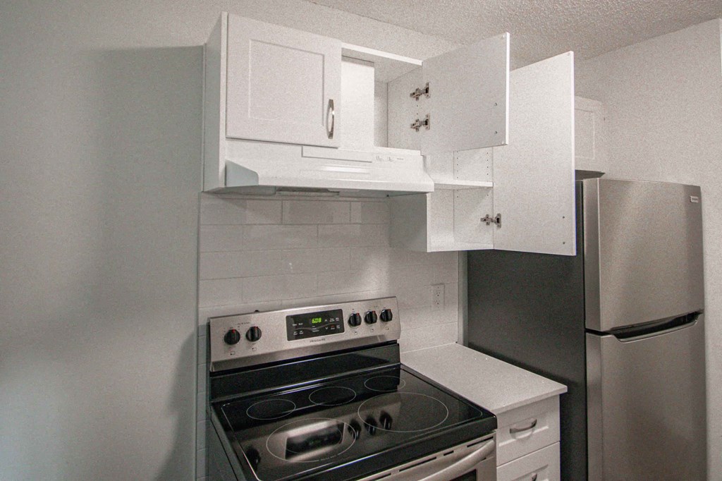 a kitchen with white cabinets and stainless steel appliances and a refrigerator