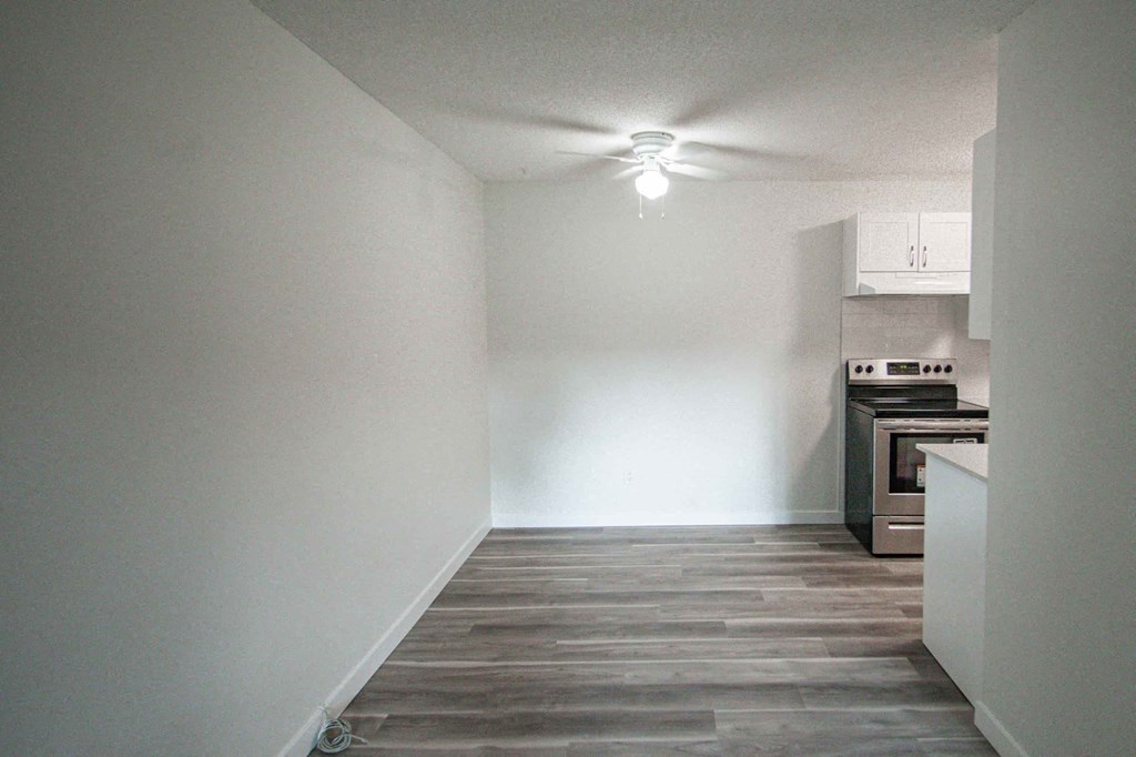 an empty room with a stove and a ceiling fan