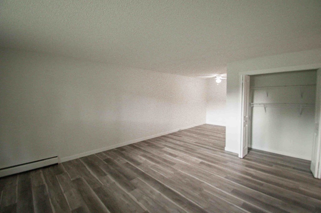an empty room with a wood floor and white walls