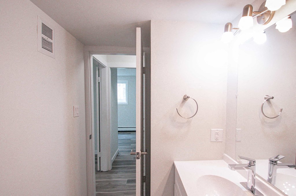 a bathroom with a mirror and a sink and a door to a hallway