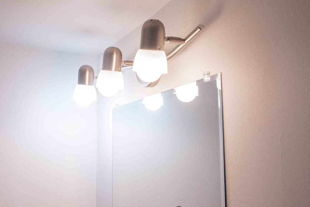 a bathroom mirror with a light fixture on the wall
