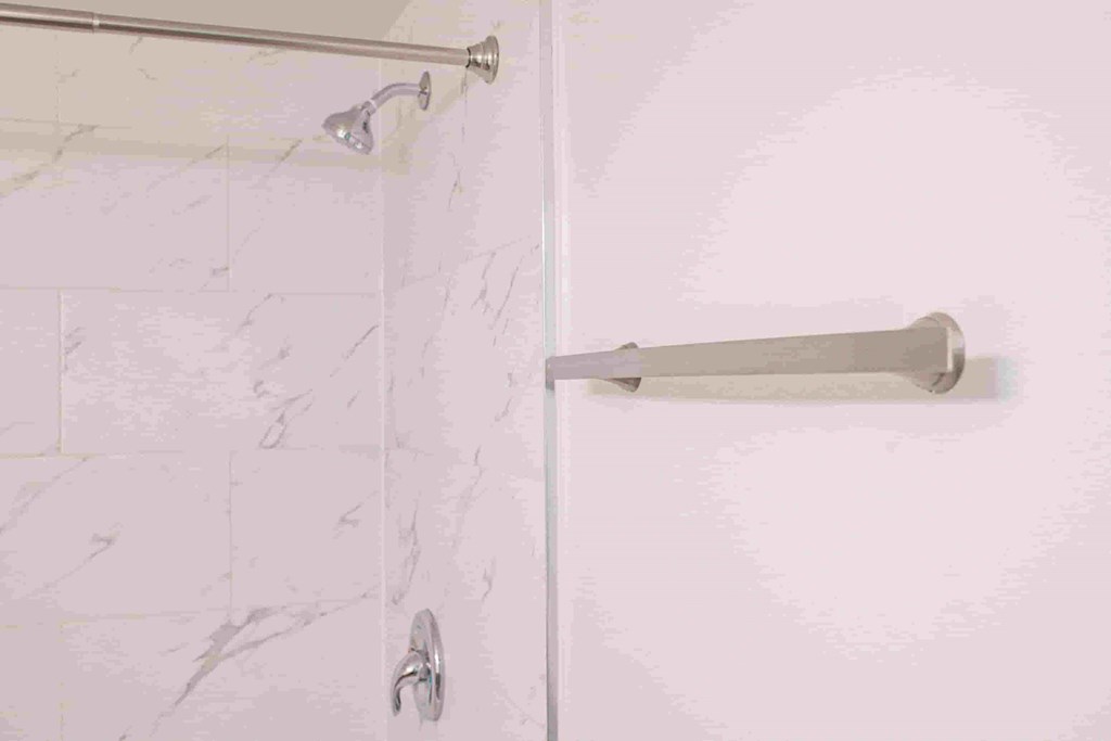 a white bathroom with a white shower curtain and a handle on the door