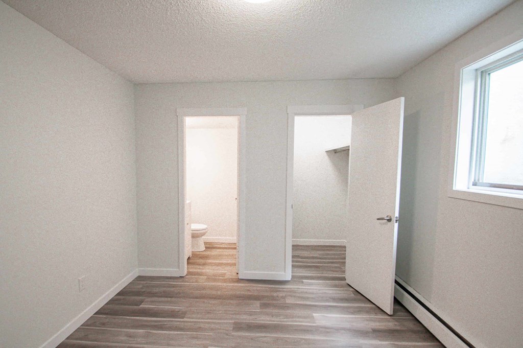 an empty room with a door to a bathroom and a toilet