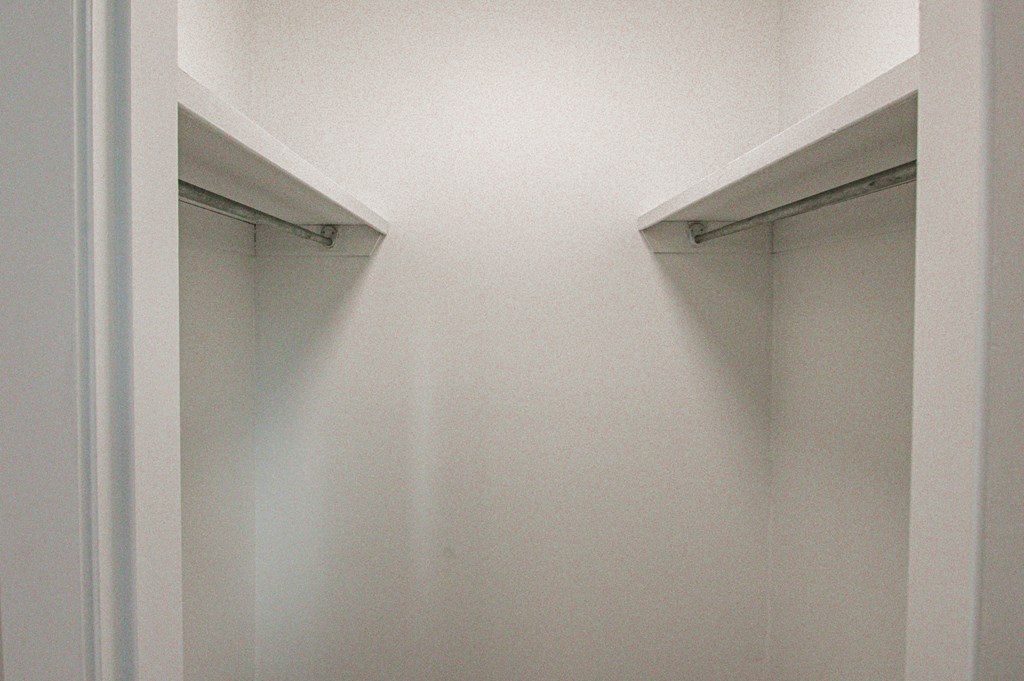 a walk in closet with two windows and a white wall