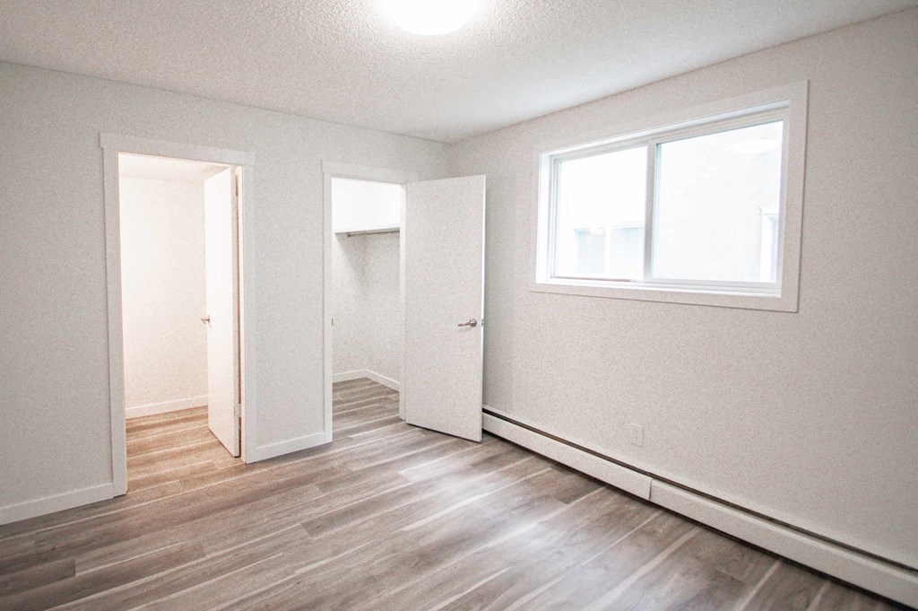 an empty room with white walls and wood floors