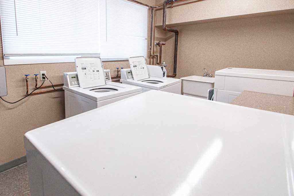 a kitchen with four washing machines and a counter with a sink