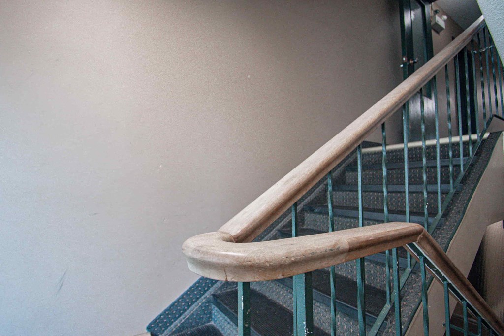 a stairwell with a wooden handrail and a metal railing with a wood handle
