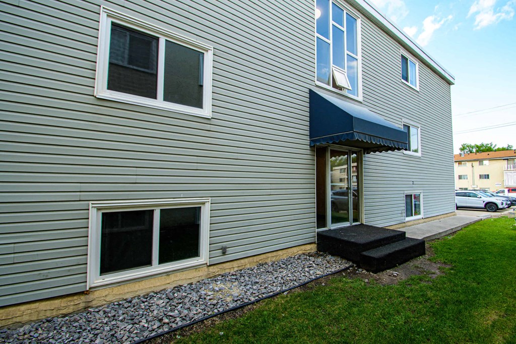the side of a house with a porch and a blue awning