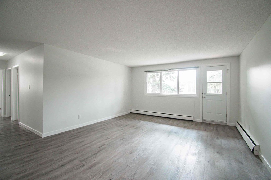 an empty living room with white walls and wood floors