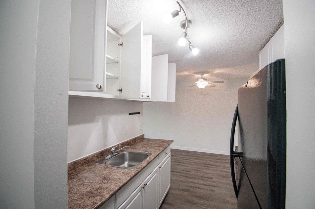 a kitchen with white cabinets and a black refrigerator