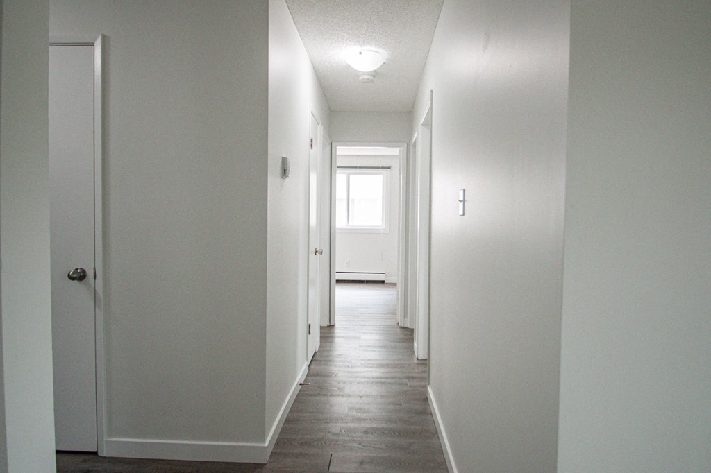 a blank white hallway with white walls and wood floors