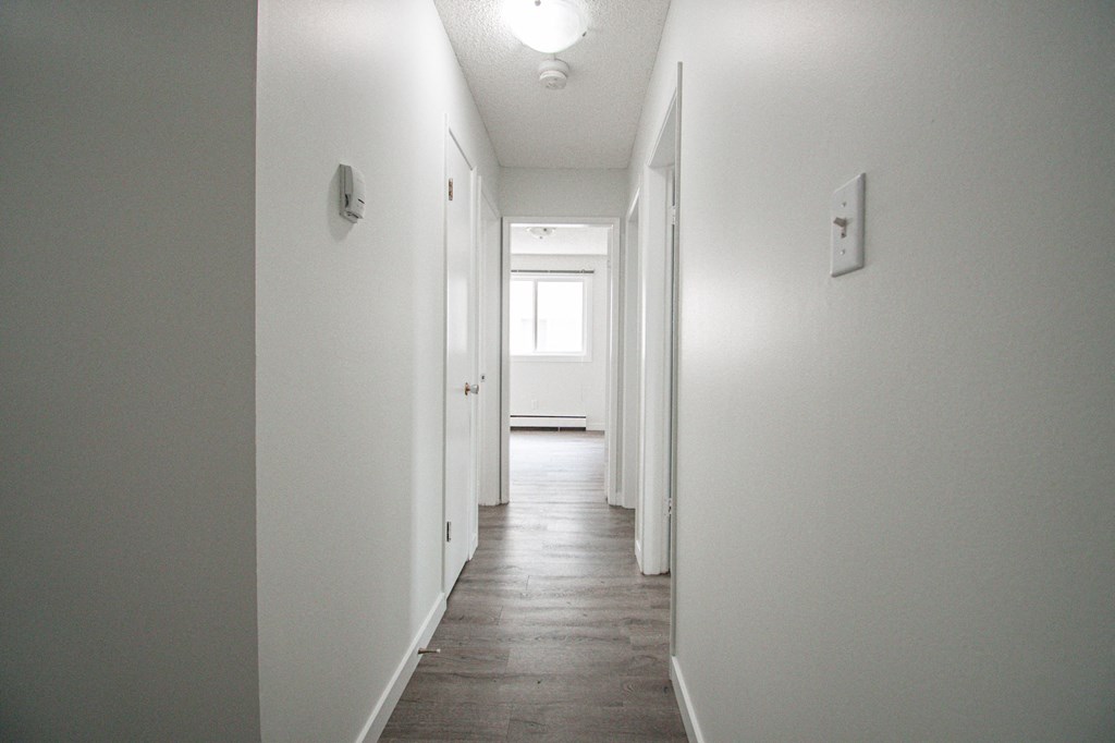 a long white hallway with white walls and wood floors