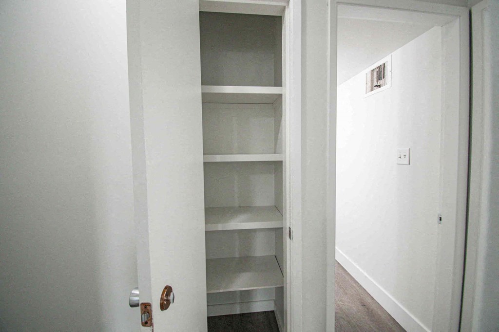 a small closet with empty shelves in a white room