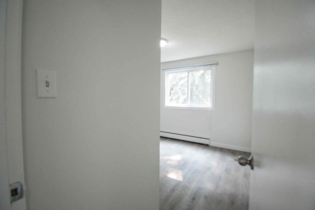 an empty living room with white walls and a window