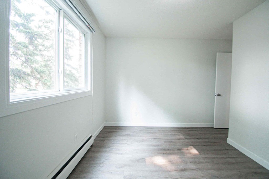 an empty room with white walls and a large window