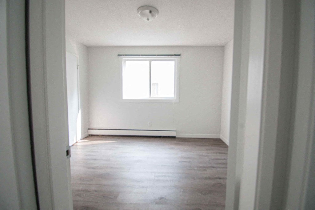 an empty room with a window and wood floors