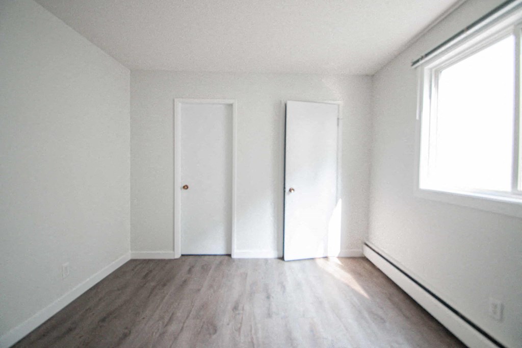 an empty room with white walls and wood floors