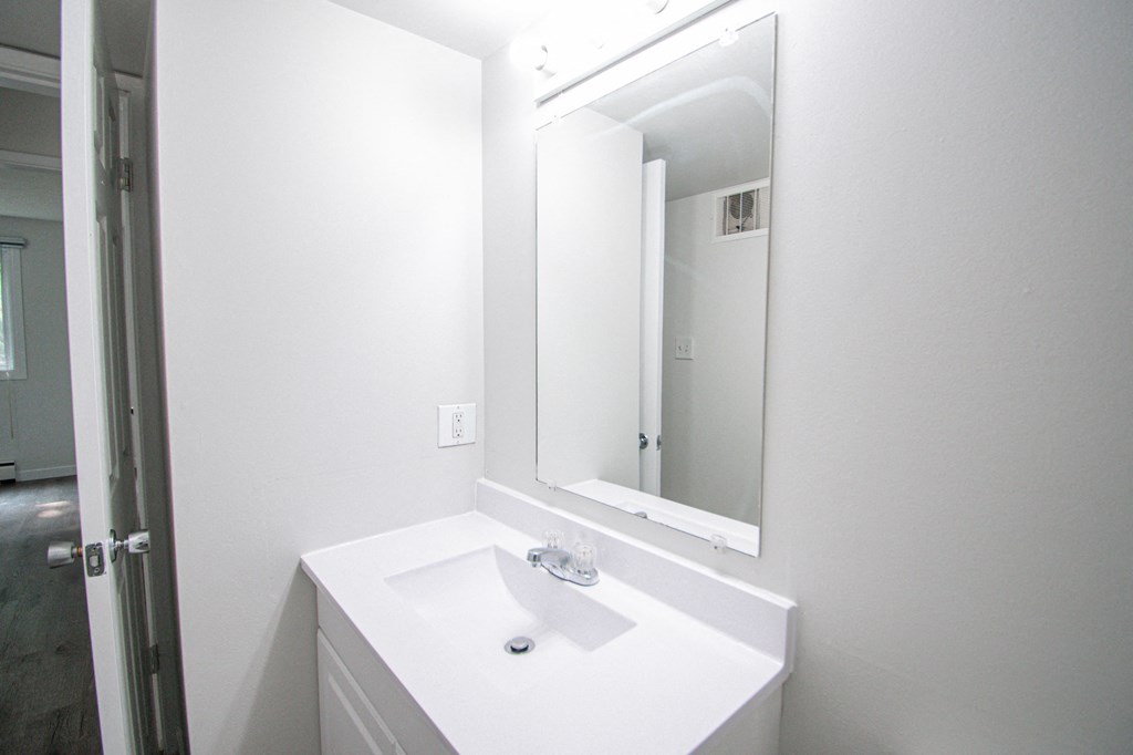 a white bathroom with a sink and a mirror
