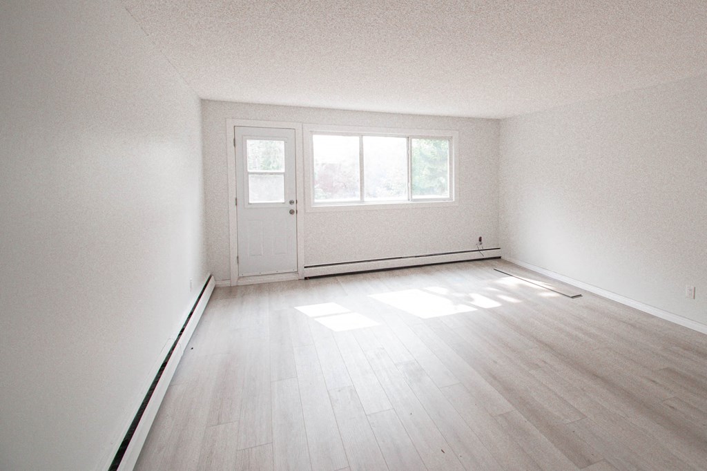 an empty living room with white walls and wooden floors