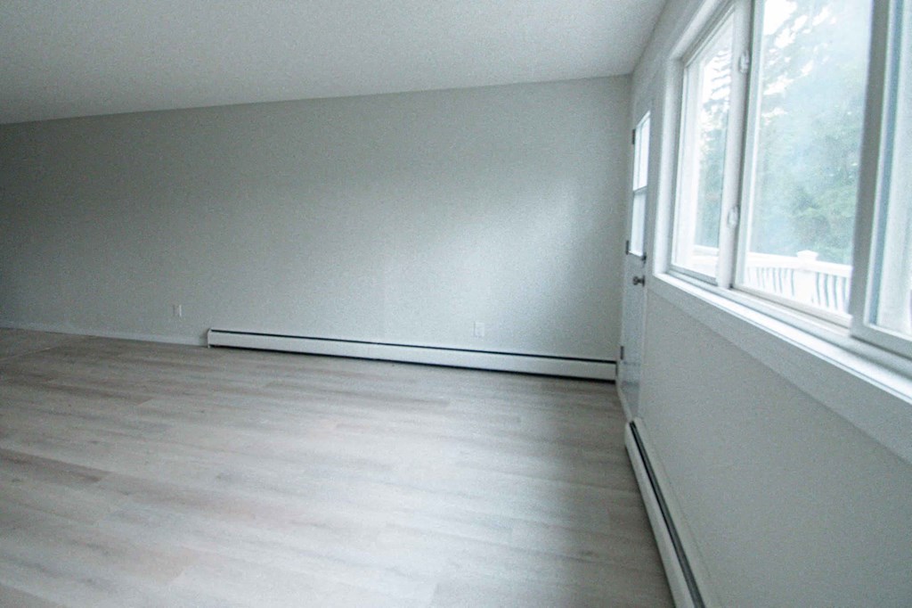 an empty room with wood flooring and large windows