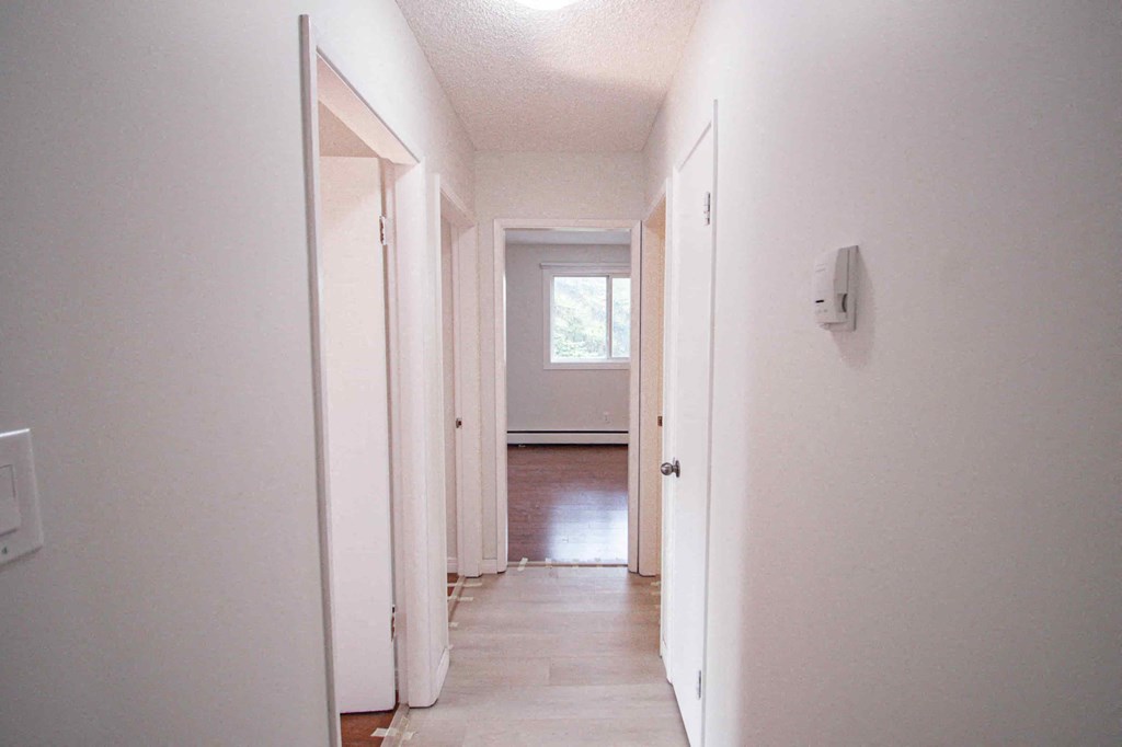 a hallway with white walls and a door to a room