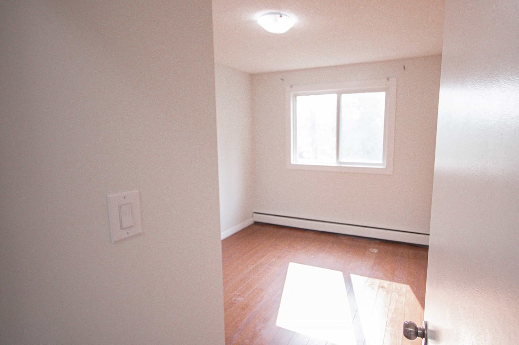 an empty room with a window and wood floors