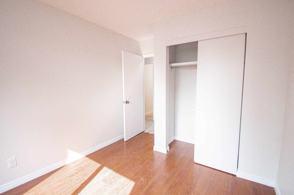 a bedroom with a door to a closet and a hard wood floor