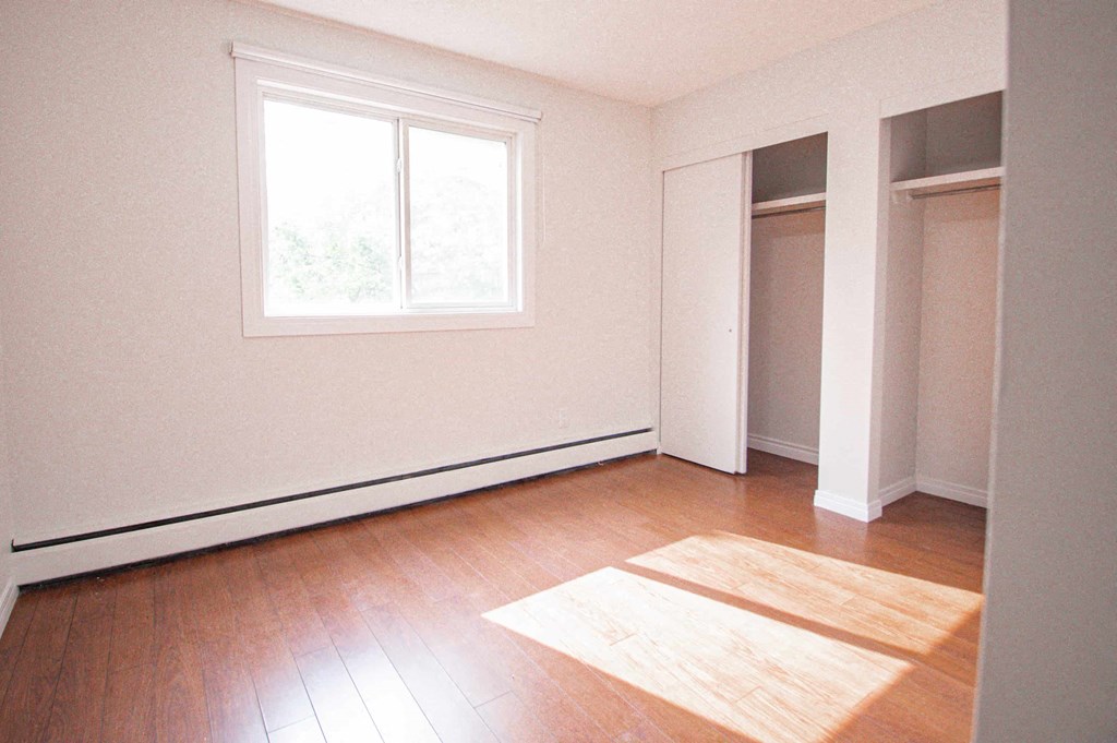 an empty room with wooden floors and a window